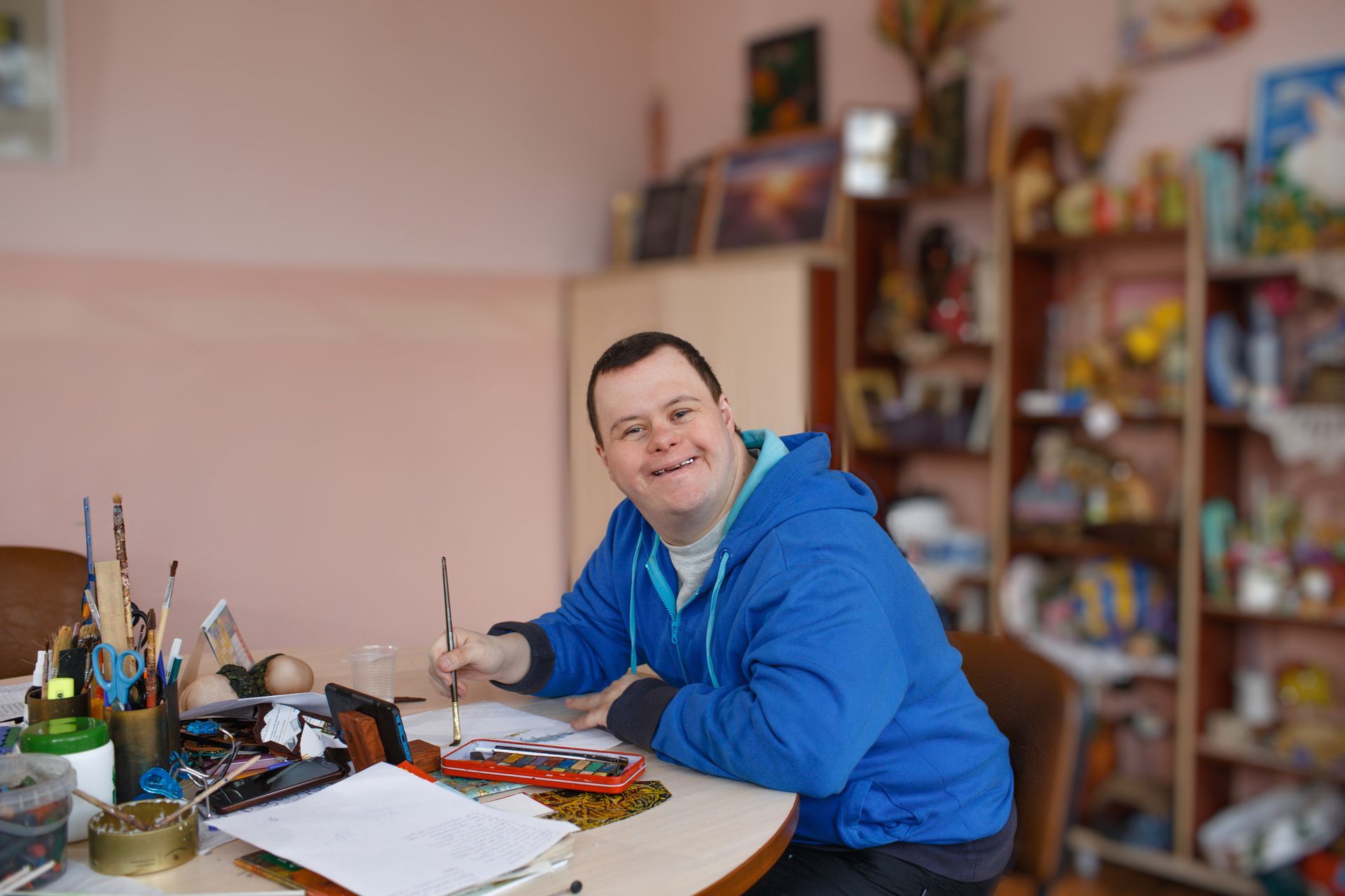 A man is sitting at a table painting with a brush.