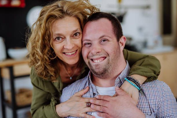 A woman is hugging a man with down syndrome and they are smiling for the camera.