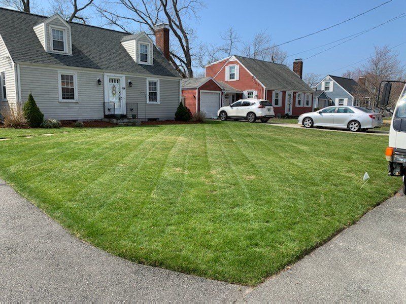 A lush green lawn in front of a house with cars parked in front of it.