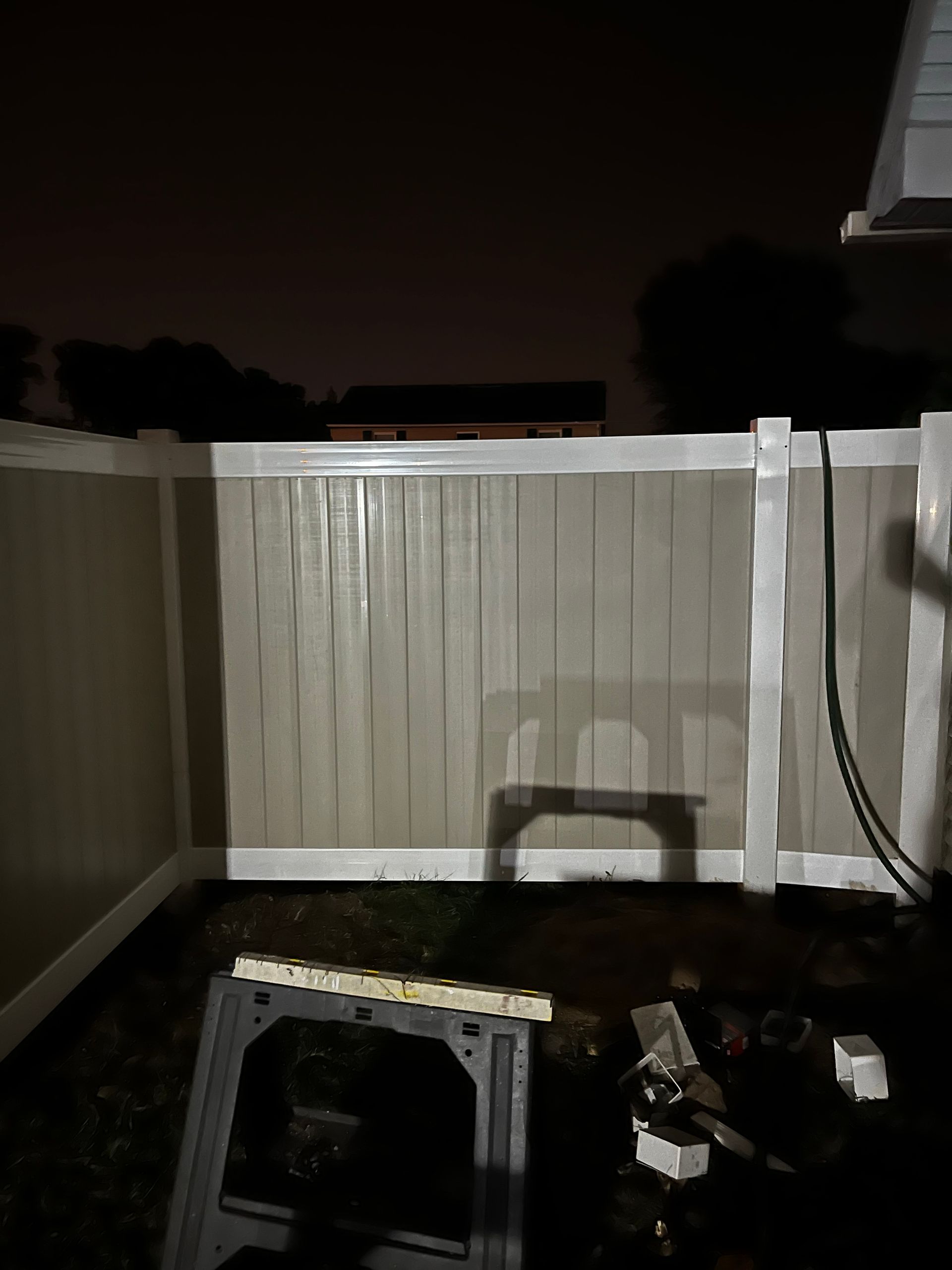 Completed white vinyl privacy fence project at night in Burlington County NJ