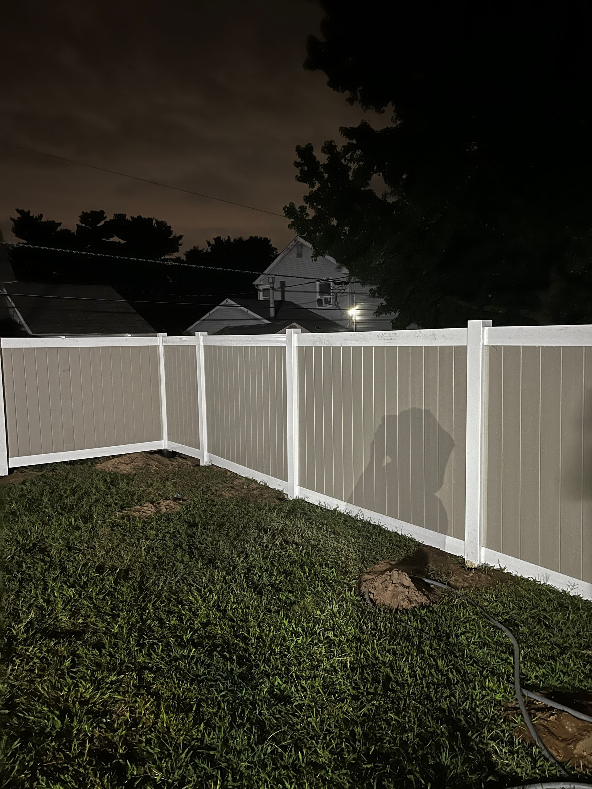 Completed backyard vinyl privacy fence at night in Burlington County NJ