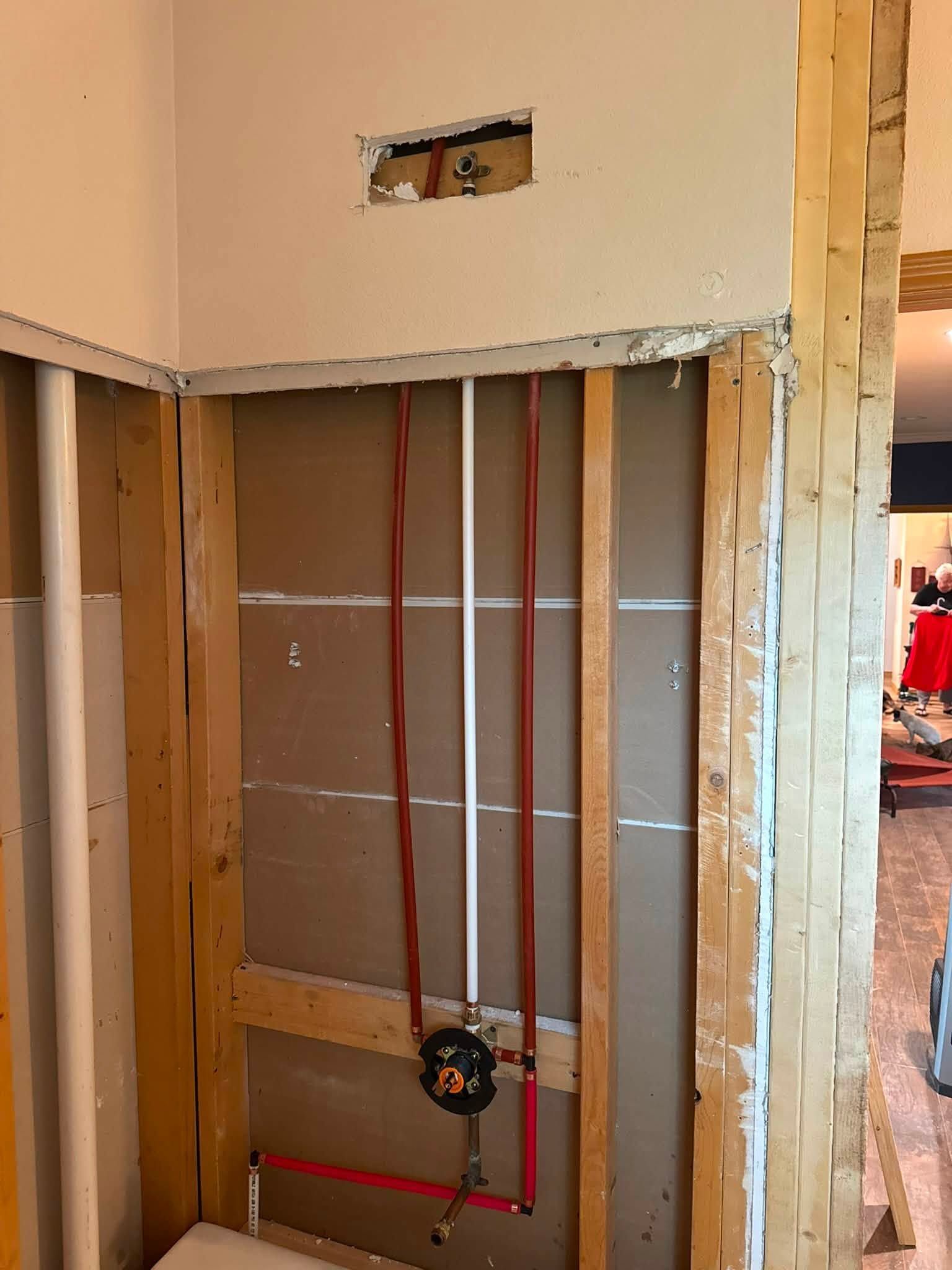 Partially finished wall with exposed studs and red plumbing pipes in a home under construction
