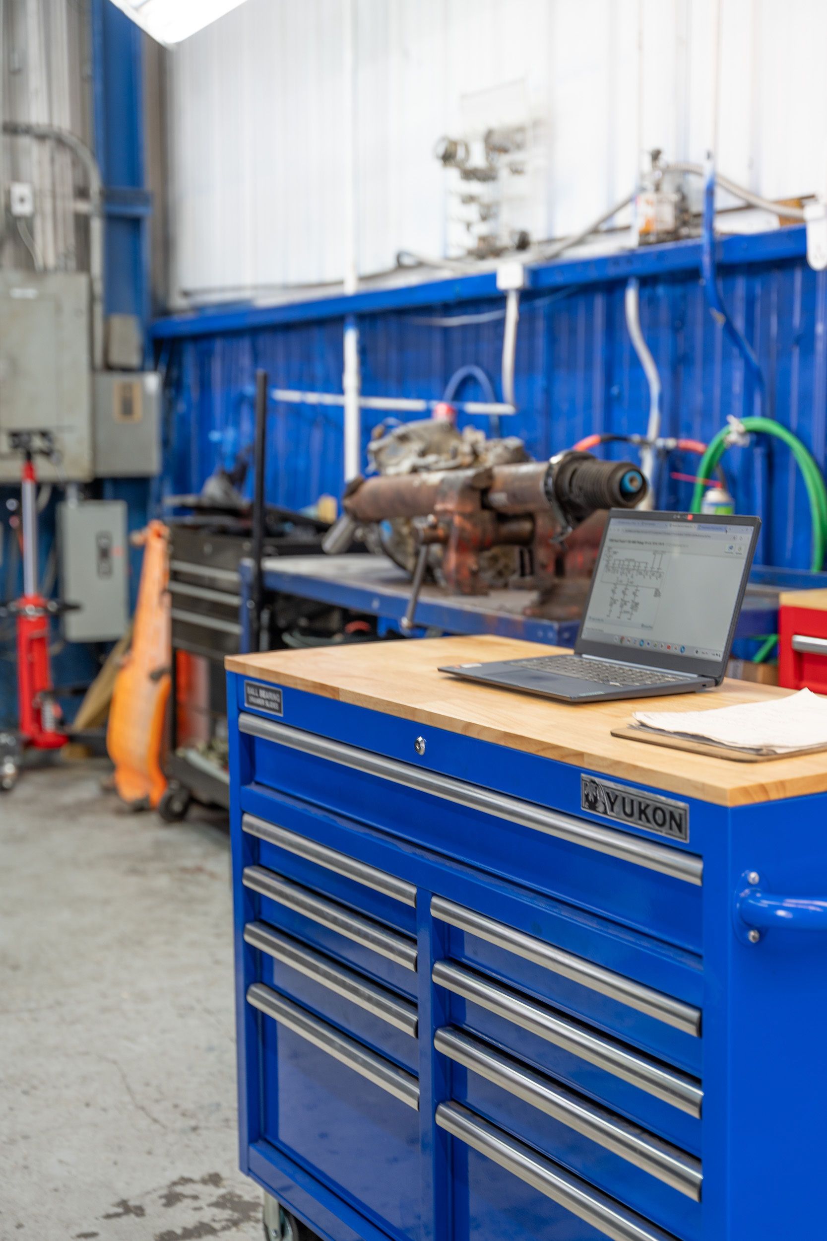 Blue tool chest with laptop in a workshop setting.