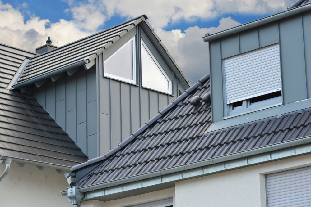 Gray Residential Roof With Triangular and Rectangular Dormers, Blue Sky — Darren Smith Roofing In Kotara, NSW