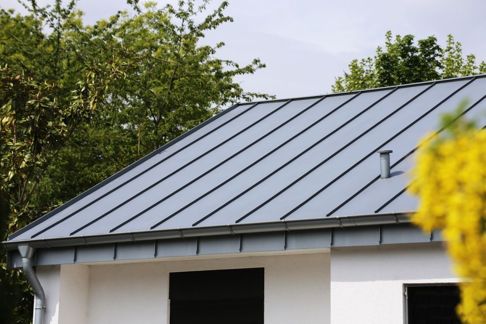 Gray Metal Roof on a White House With Trees in the Background — Darren Smith Roofing In New Lambton, NSW