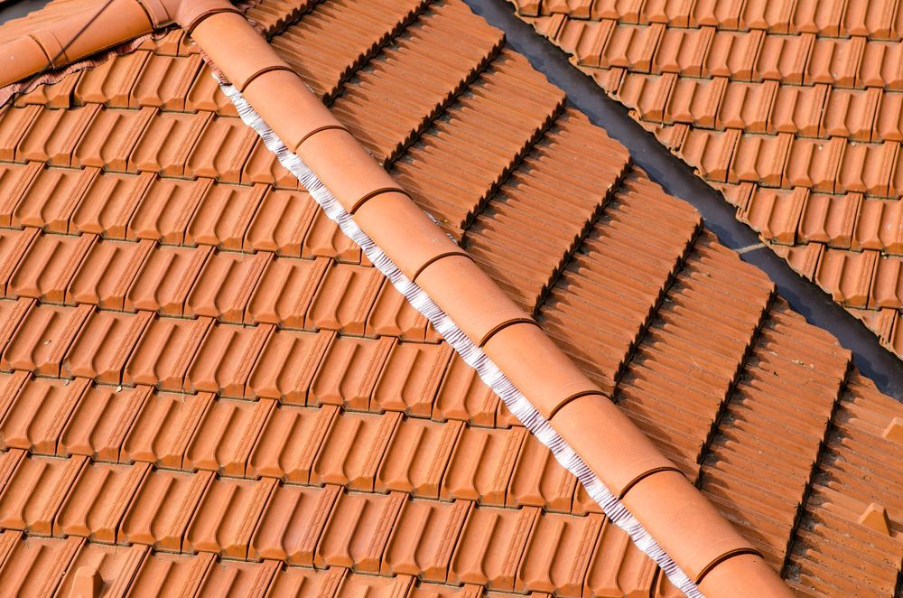 Close-up of a Terracotta Tiled Roof With a Curved Ridge, Angled Rows of Tiles — Darren Smith Roofing In Charlestown, NSW