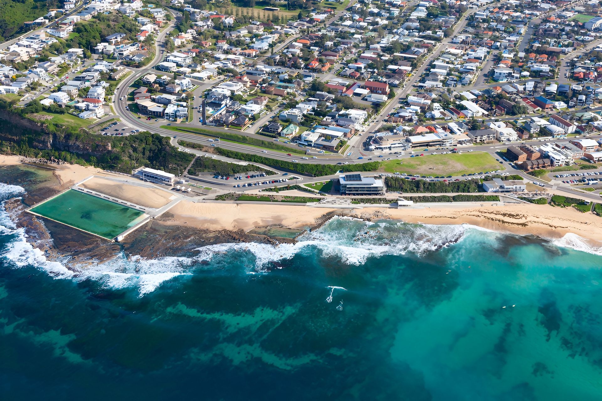 Aerial View of a Coastal Town With a Beach, Ocean, and Swimming Pool — Darren Smith Roofing In Merewether, NSW