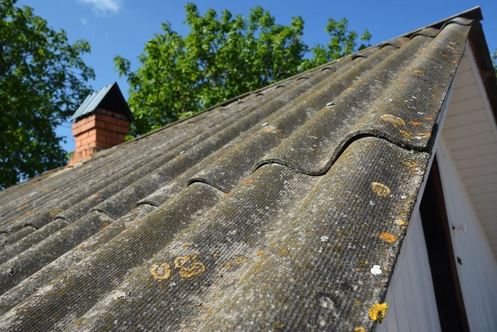 Close-up of a Weathered, Gray Corrugated Roof With a Brick Chimney — Darren Smith Roofing In Glendale, NSW
