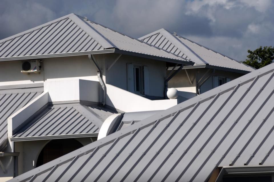 Gray Metal Roofs on a White Building Under a Cloudy Sky — Darren Smith Roofing In Glendale, NSW
