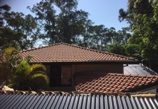 House With Red Tile Roof, Seen Behind a Corrugated Metal Roof — Darren Smith Roofing In Glendale, NSW