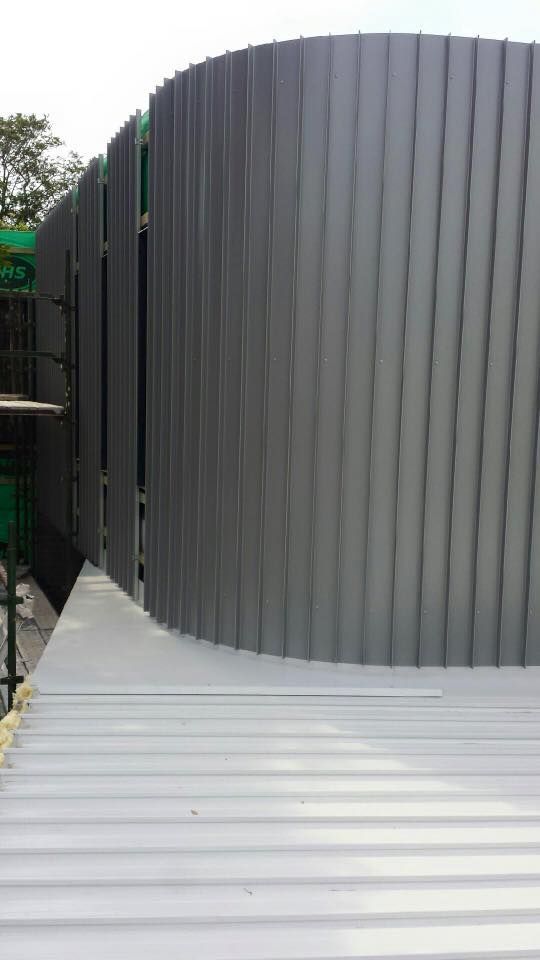 Curved Building Exterior With Gray Corrugated Metal Siding — Darren Smith Roofing In Charlestown, NSW