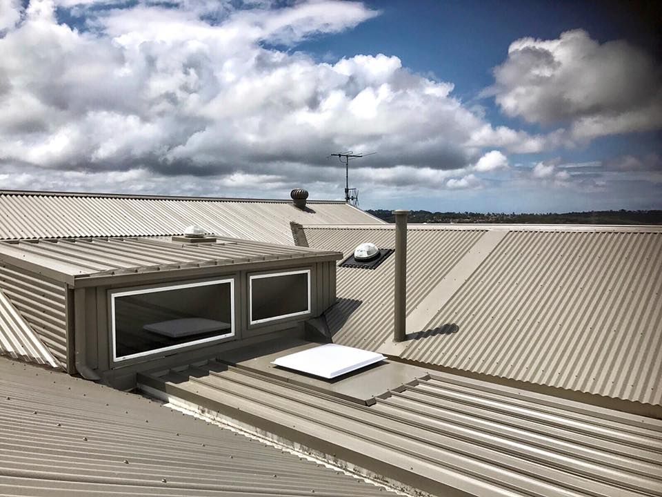 A rooftop with corrugated metal, a box-like structure with windows — Darren Smith Roofing In Glendale, NSW