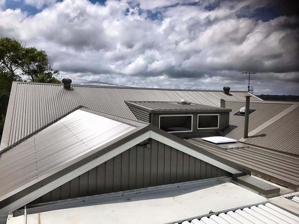 Gray metal roofs on a white building — Darren Smith Roofing In Glendale, NSW