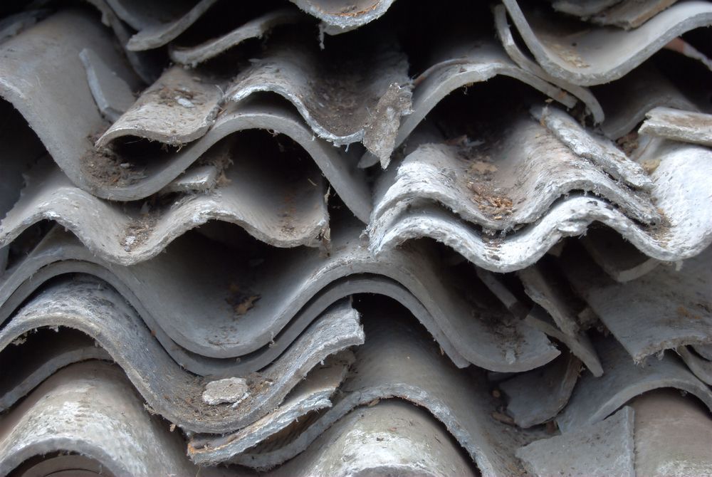 Pile of Weathered, Gray Corrugated Asbestos Roofing Tiles — Darren Smith Roofing In Glendale, NSW