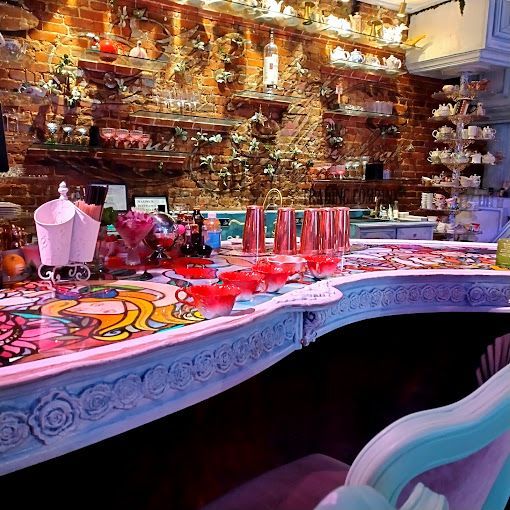 Bar with colorful counter and brick wall decorated with tea cups and flowers.