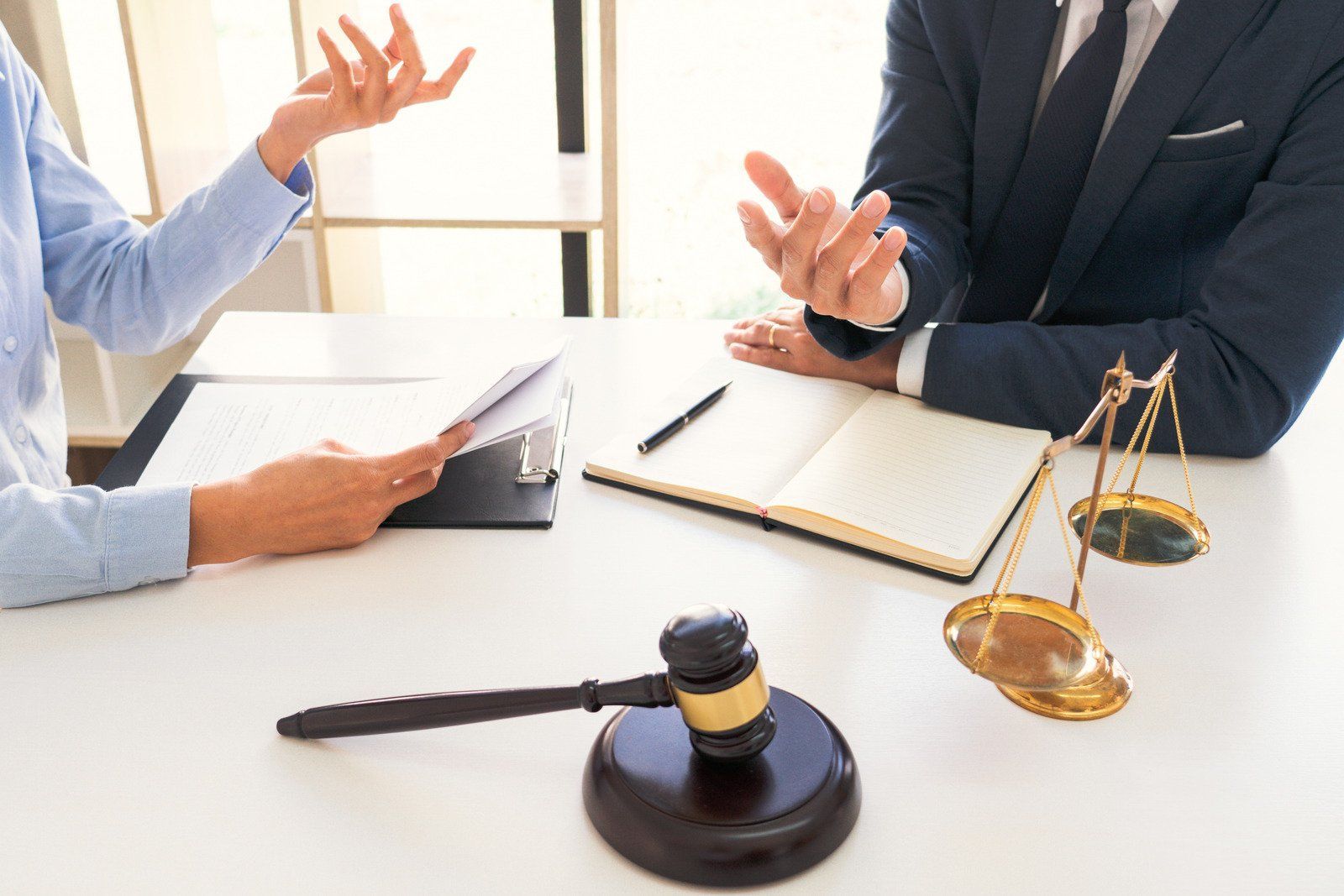 Two people in discussion at a desk with a gavel and scales of justice.