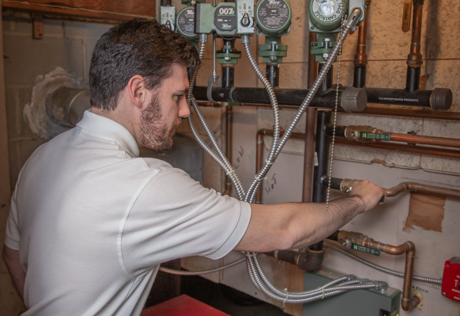 A man is working on a plumbing system in a basement.