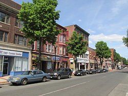 A row of cars are parked on the side of a city street.