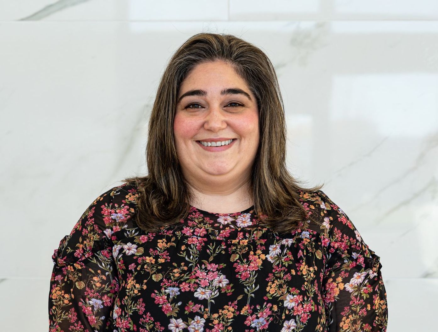 A woman in a floral shirt is smiling for the camera.
