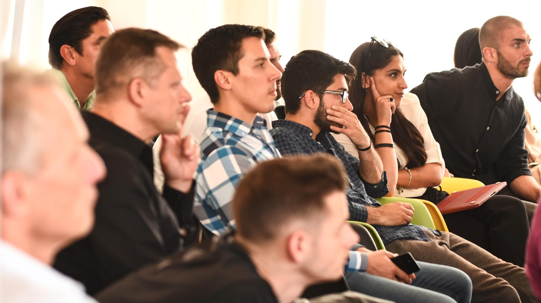 A group of people are sitting in a row listening to a presentation.