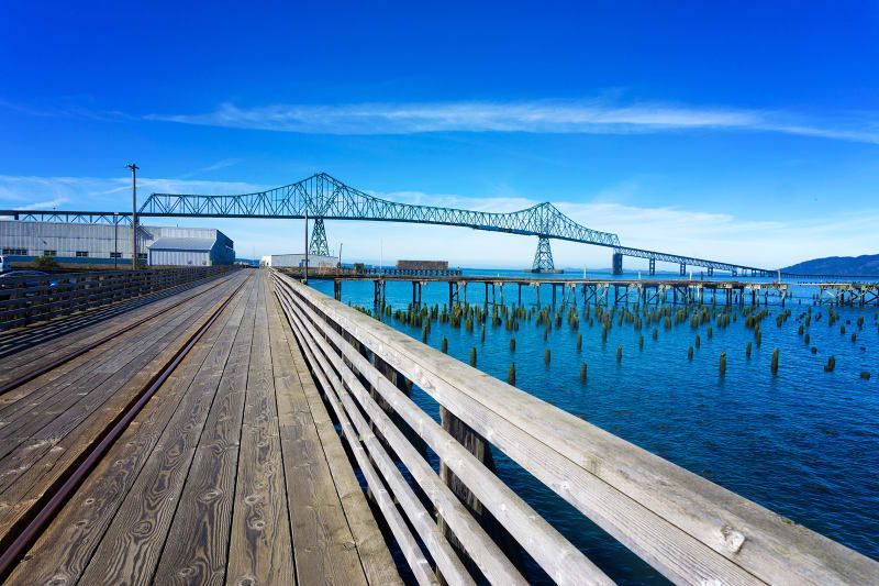 A wooden pier overlooking a body of water with a bridge in the background.