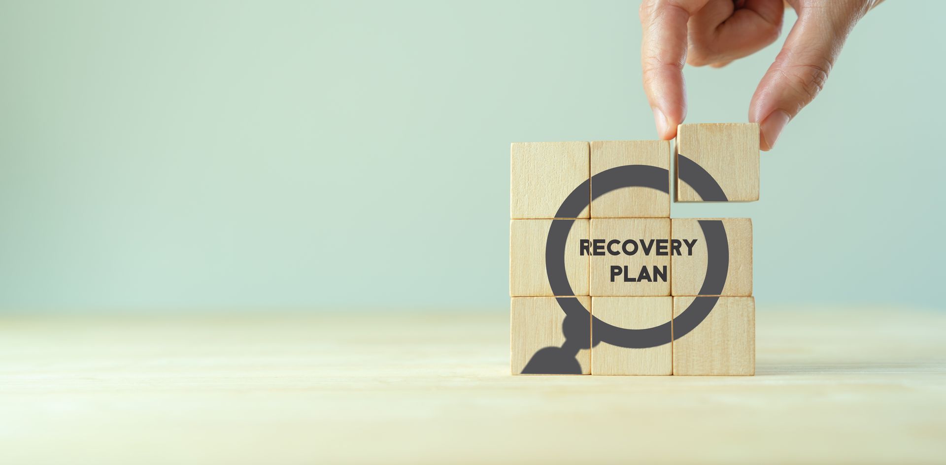 eine hand hält einen holzwürfel mit dem wort recovery plan darauf