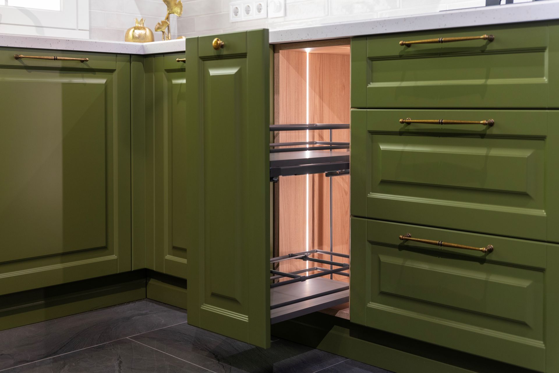 Open a drawer in a green kitchen cabinet.