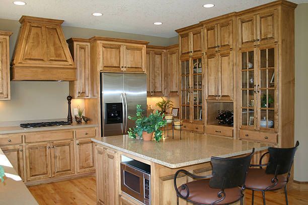 Modern kitchen with natural wood cabinets, granite island countertop, and stainless steel fridge.
