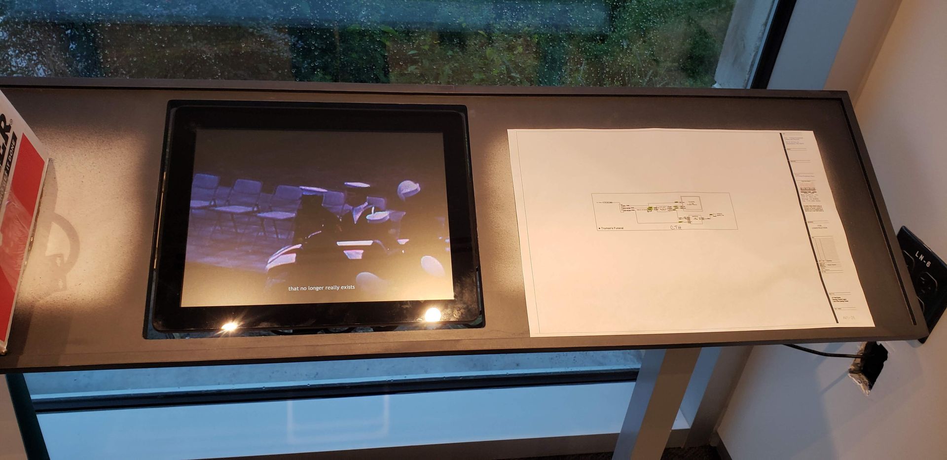 A computer monitor is sitting on a table next to a piece of paper.