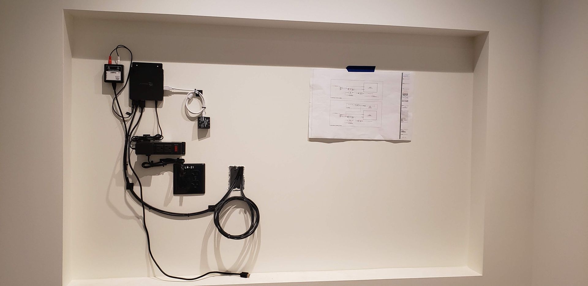 A white wall with a bunch of wires hanging from it.