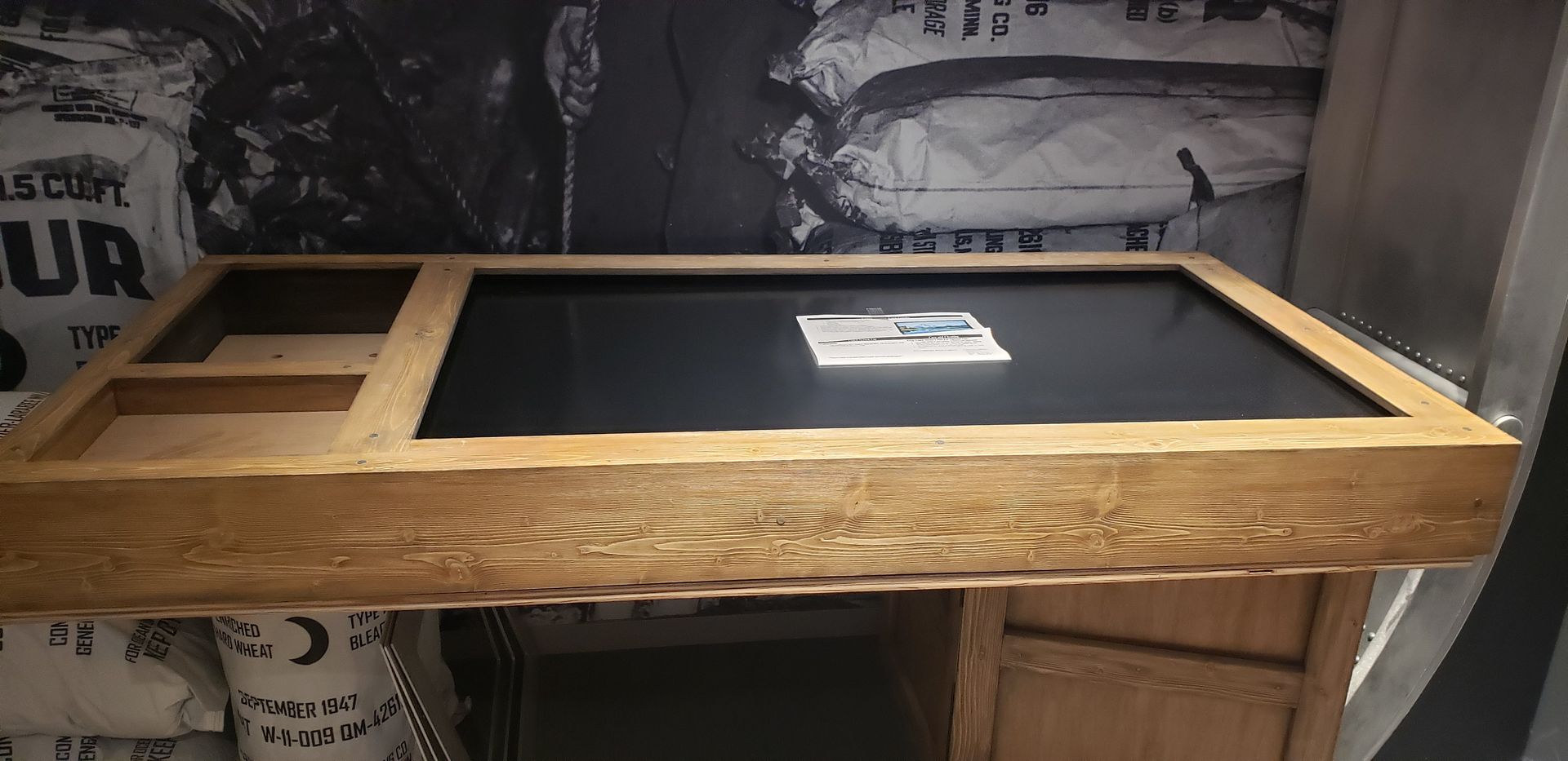 A wooden table with a black table top is sitting in a room.