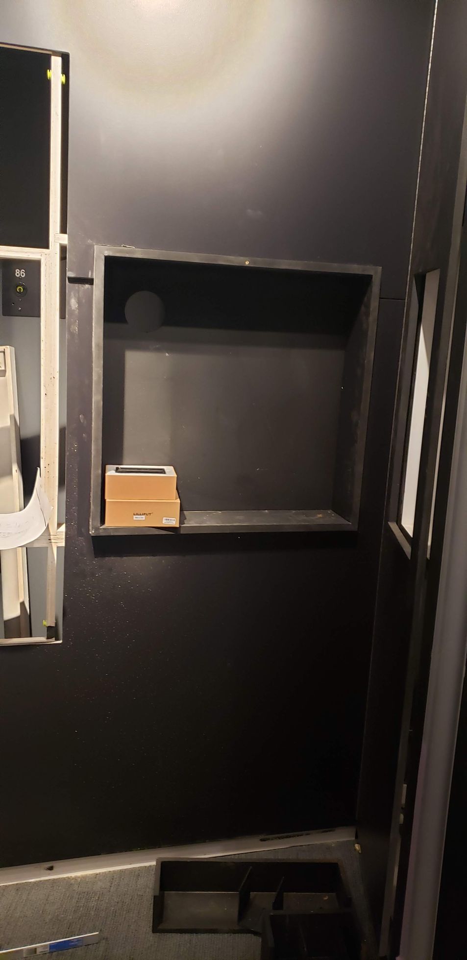 A black wall with a shelf in the middle of it.