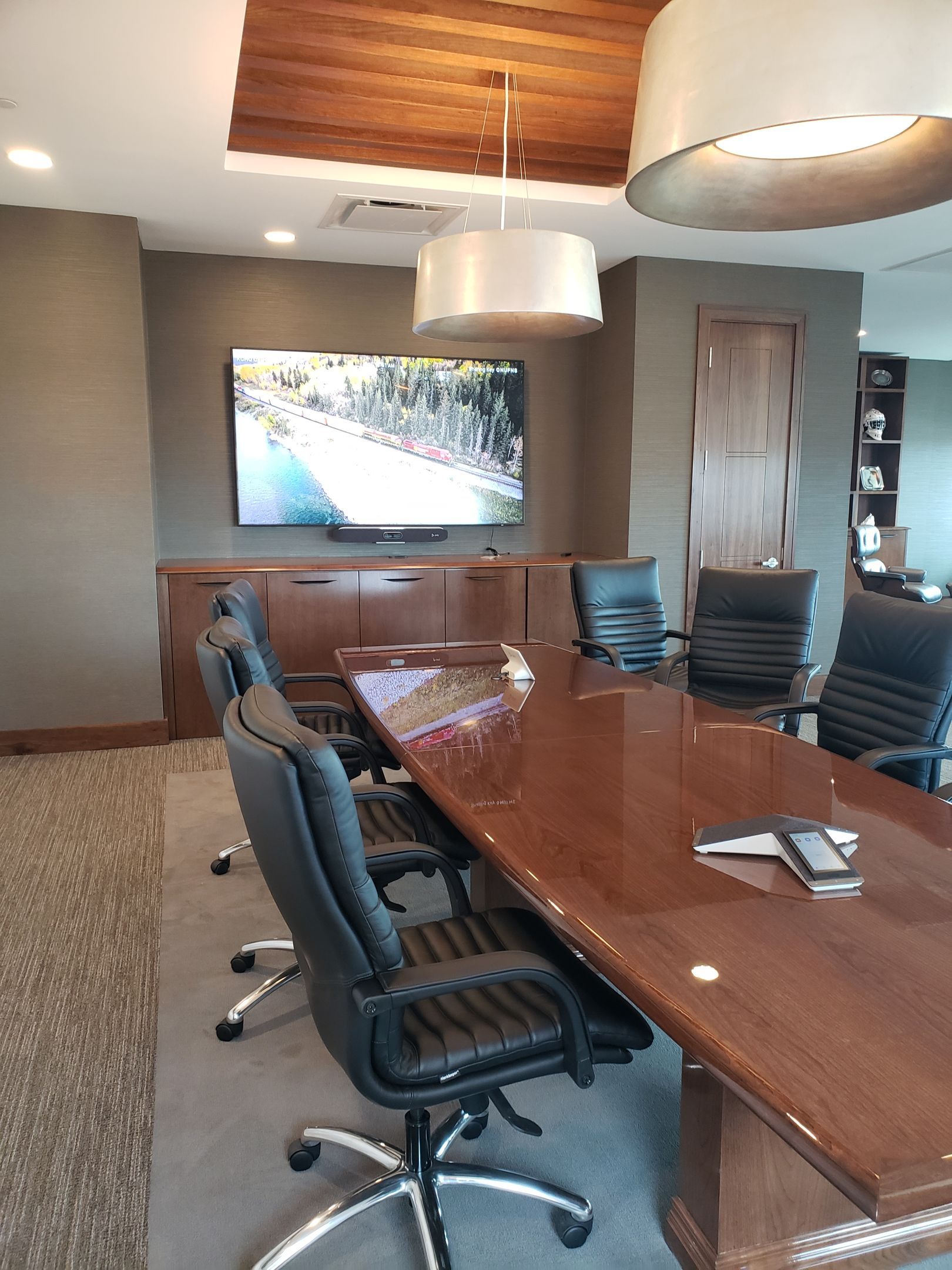 A conference room with a long table and chairs and a flat screen tv.
