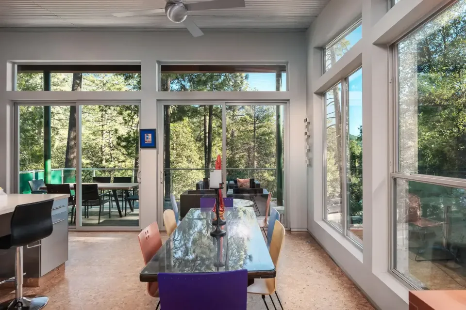 A dining room with a table and chairs and lots of windows