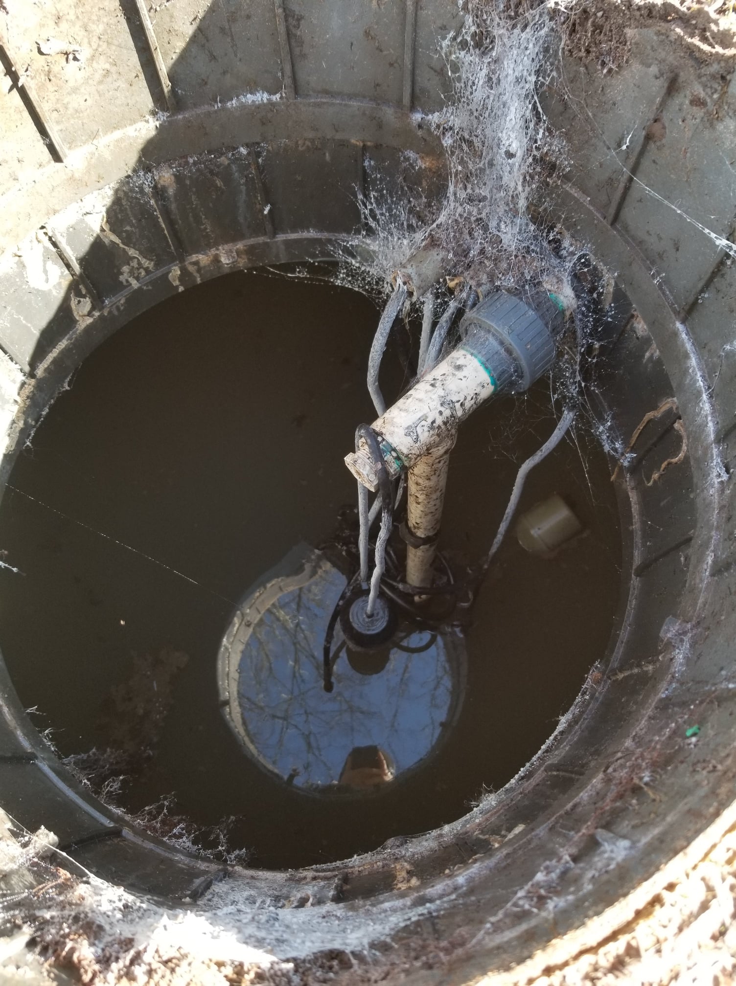 Looking down into a well, containing water and a pump.