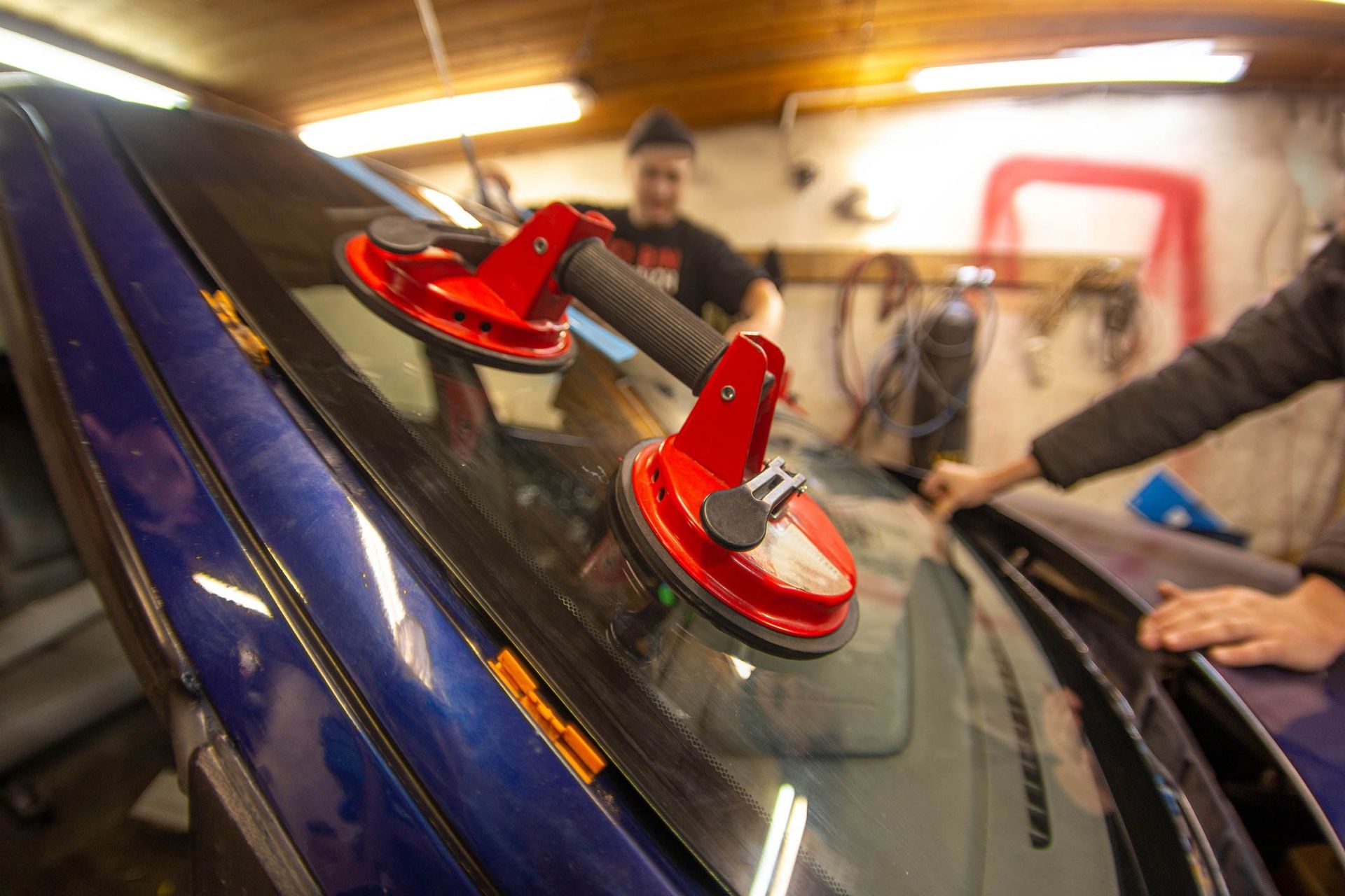 A Man Is Installing a Windshield on A Blue Car | Perth, WA | Perth Windscreens and Autoglass
