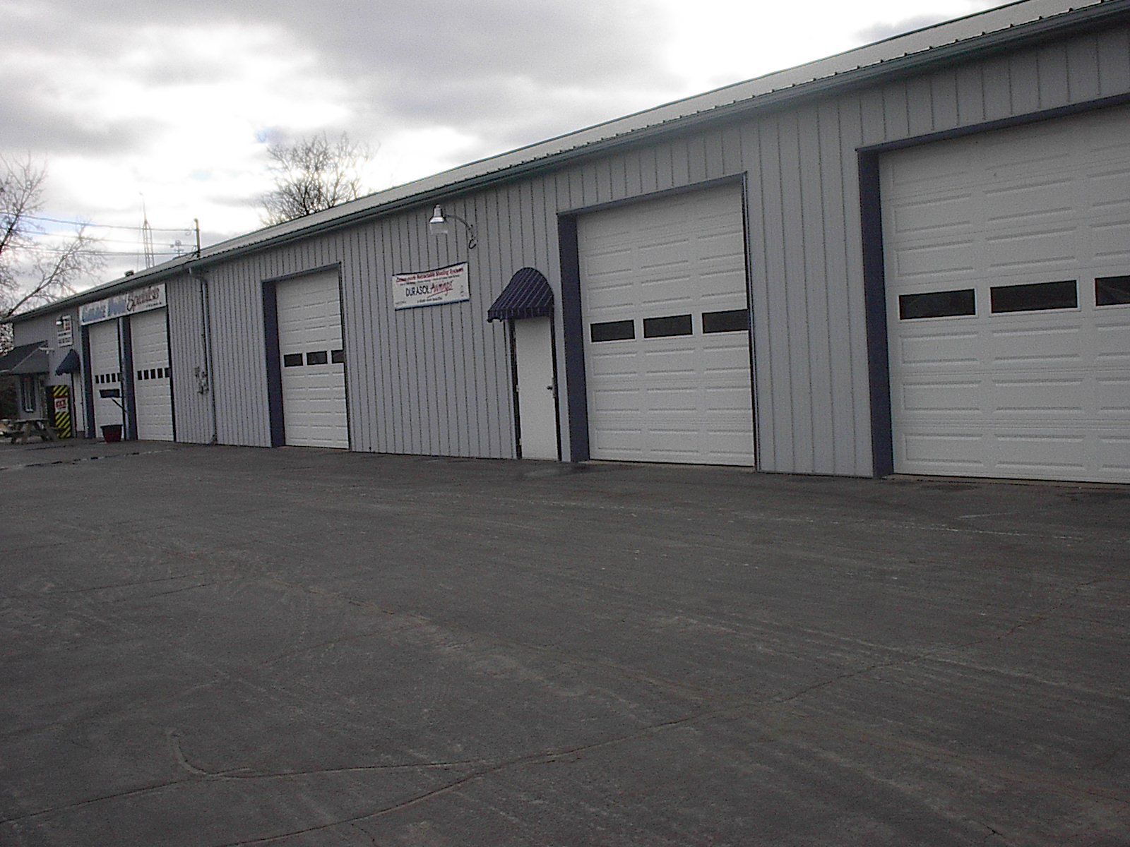 Row of gray industrial garage units with closed white doors along an empty paved lot