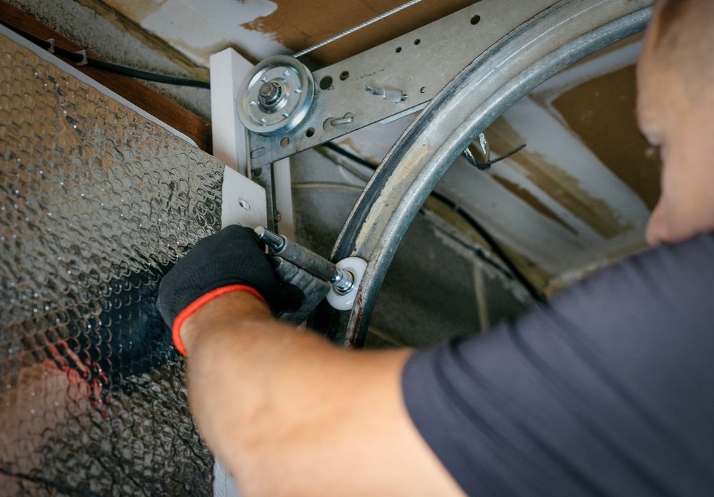 Person in black gloves tightening a metal cable mechanism inside a cabinet or appliance.