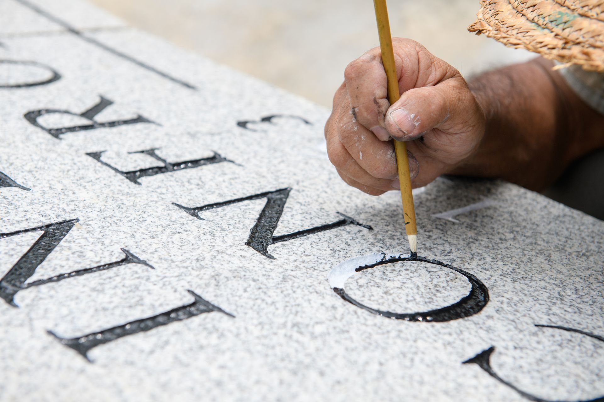 Stone mason painting on grave stone, showcasing his expertise in customized headstones. Stone mason painting on grave stone, showcasing his expertise in customized headstones.
