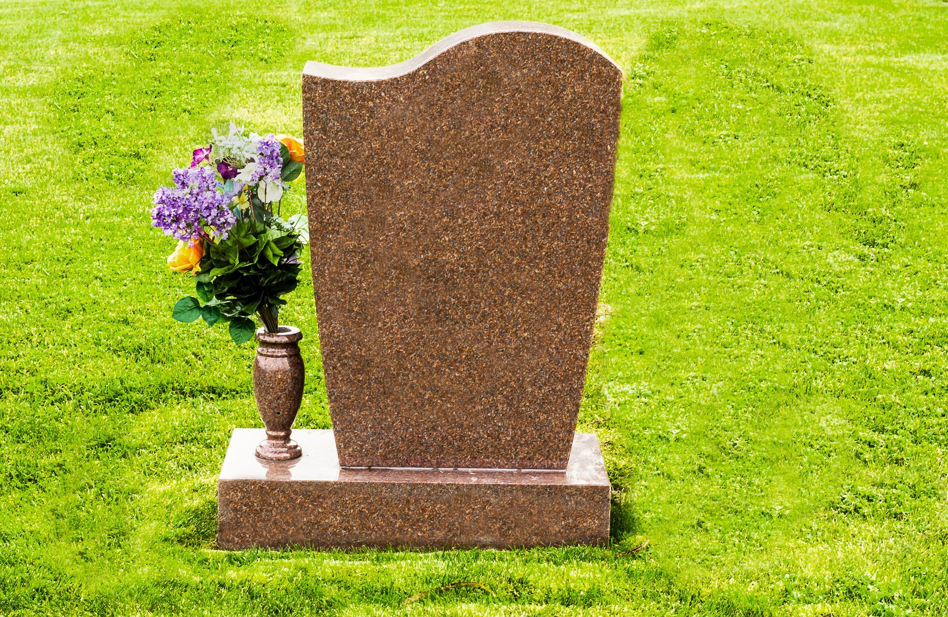 Custom grave headstone adorned with flowers | Mountain View, AR