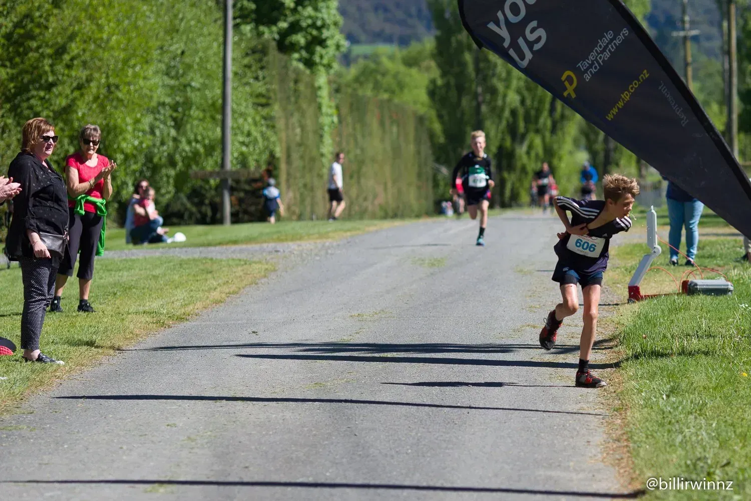 A young boy is running down a road in a race.