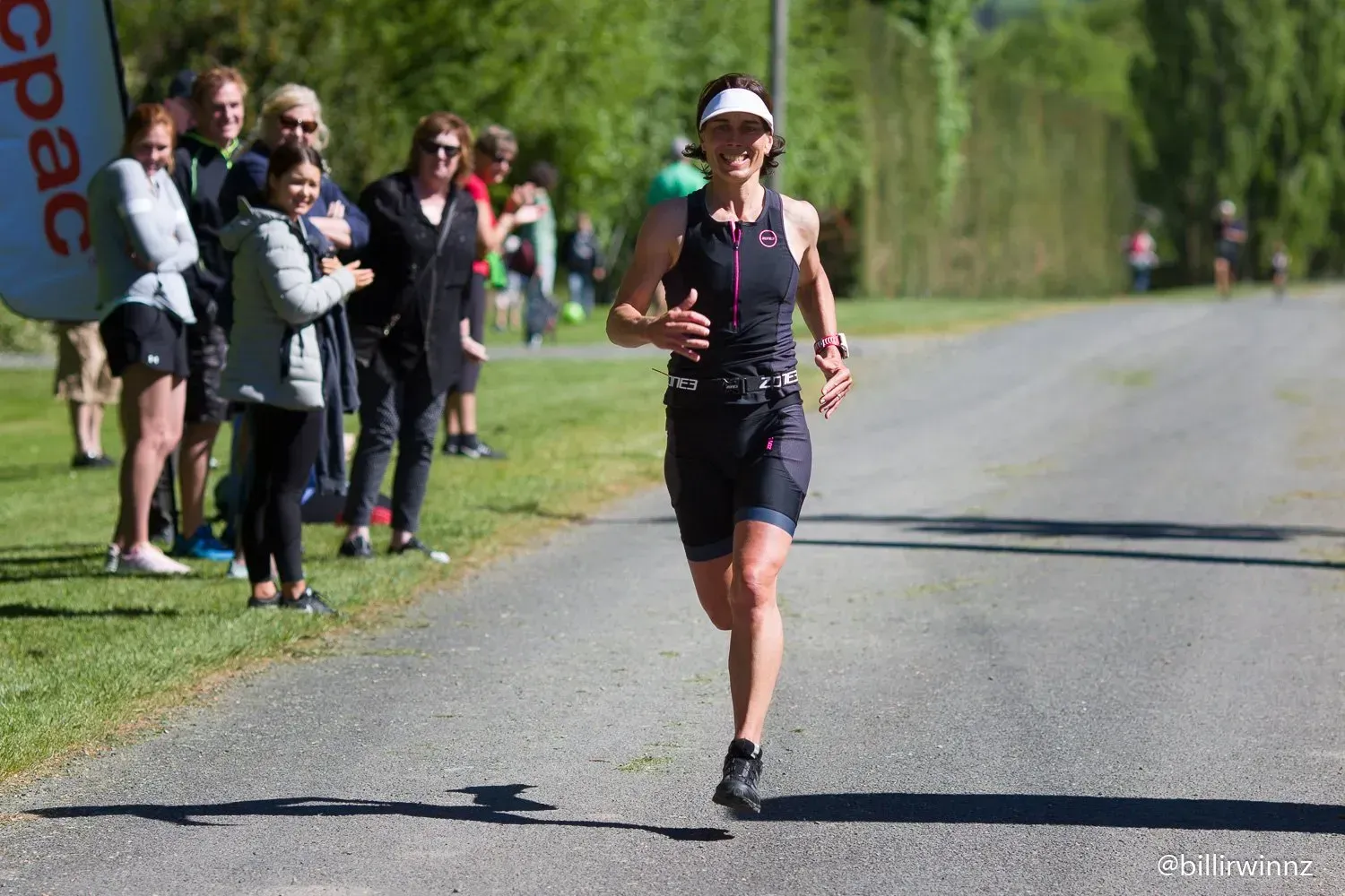 A woman is running down a road in front of a crowd of people.