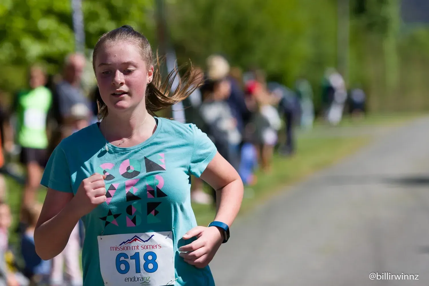A young girl is running a race on a road.