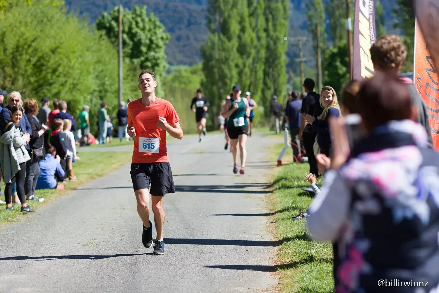 A man in a red shirt is running down a road.