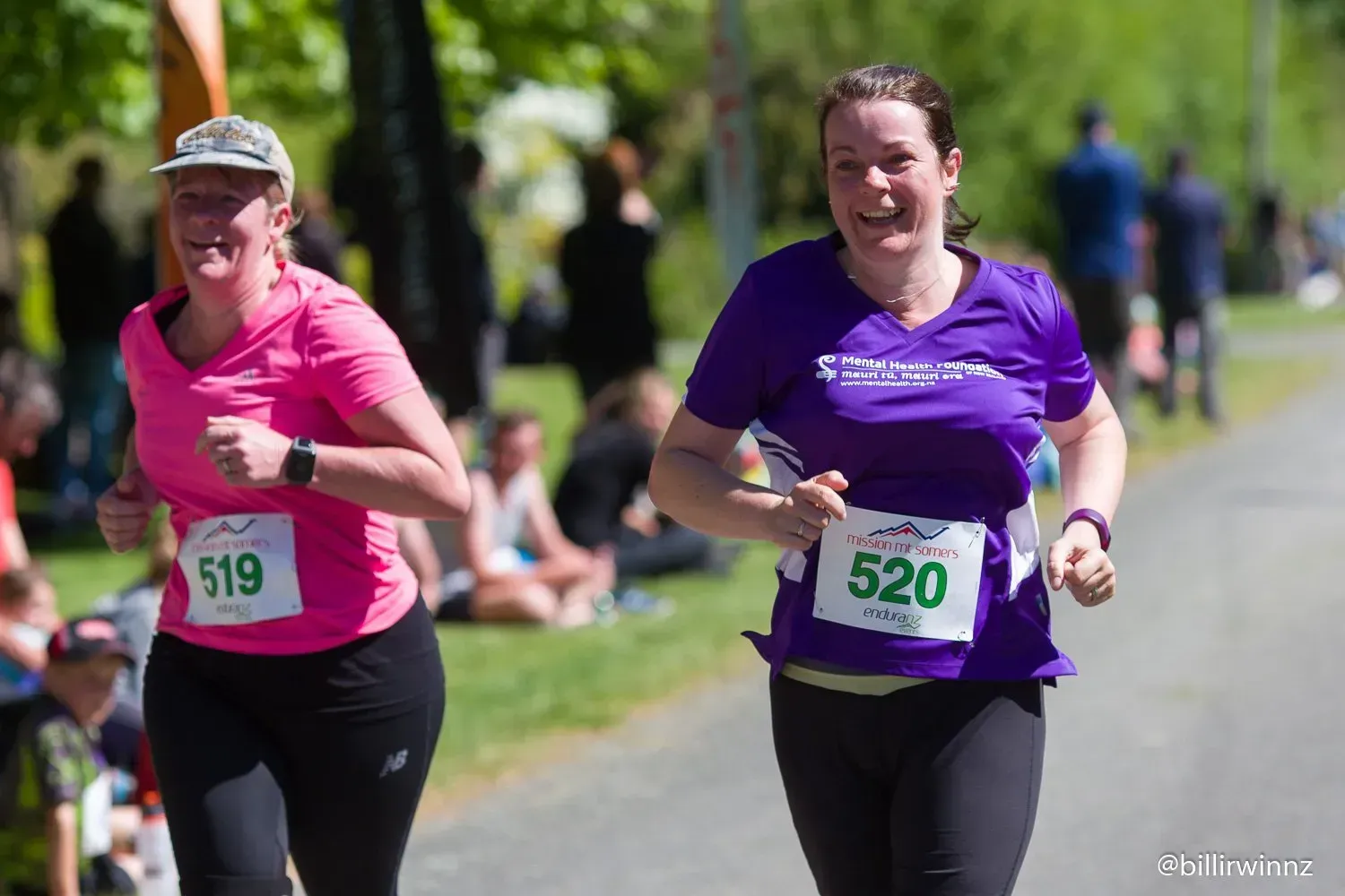 Two women are running a race in a park.