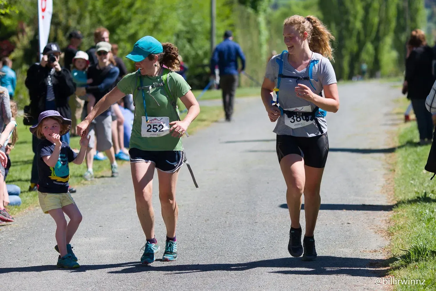 A group of people are running down a road holding hands.