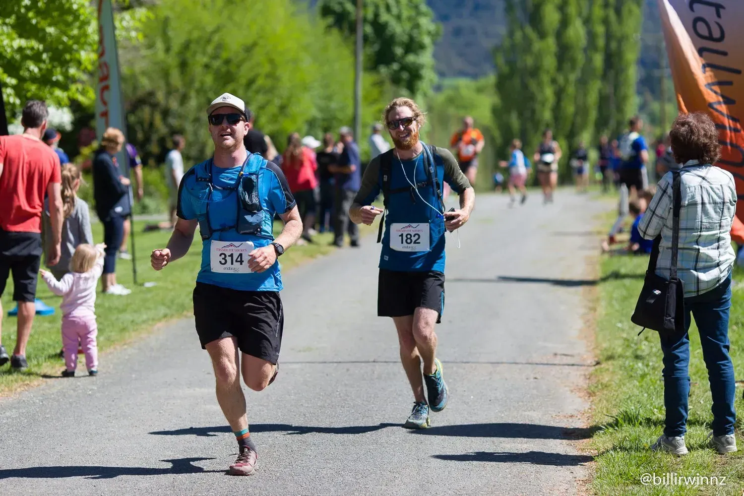 Two men are running down a road in a race.