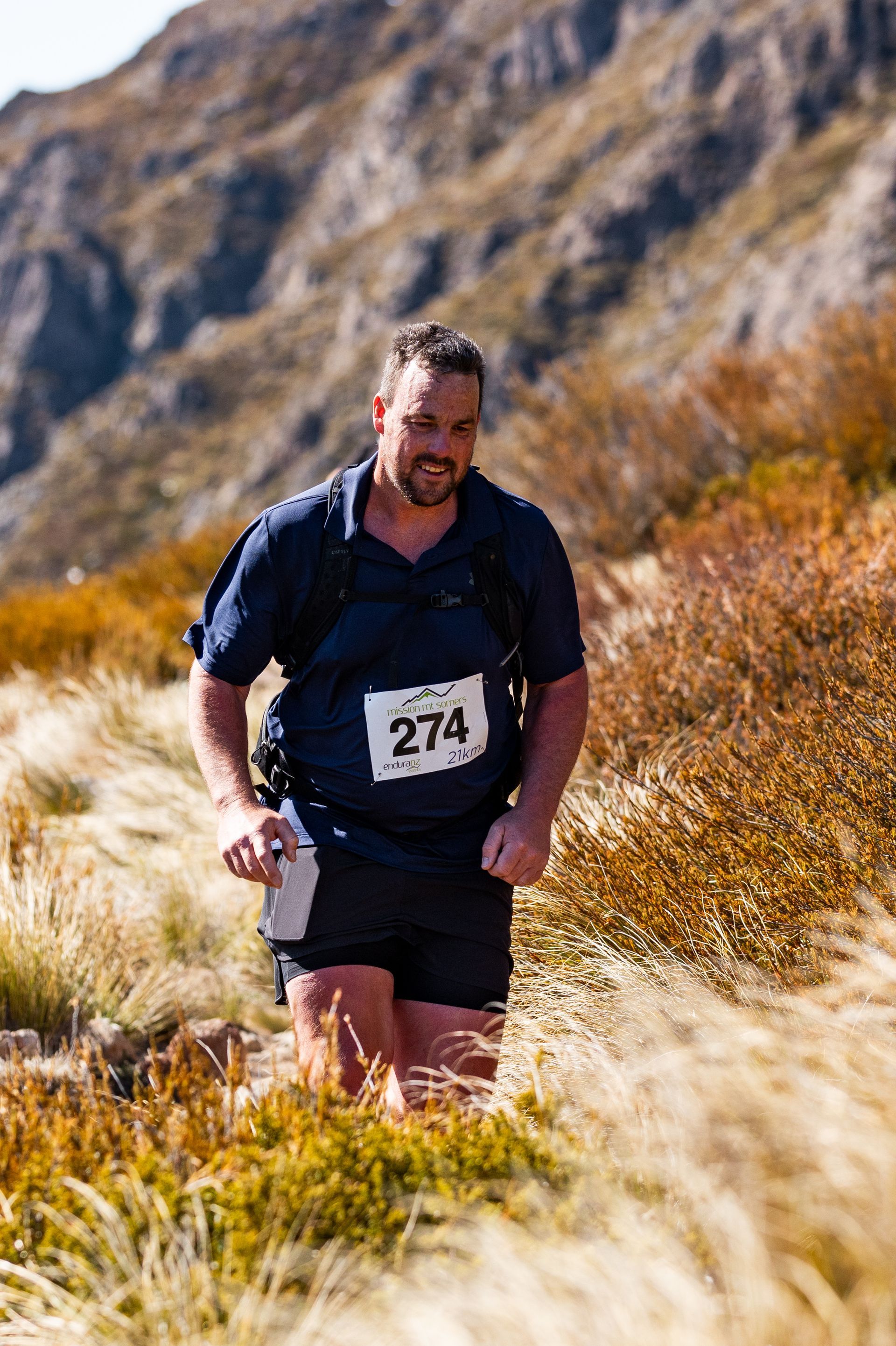 A man is running in a field with a mountain in the background.