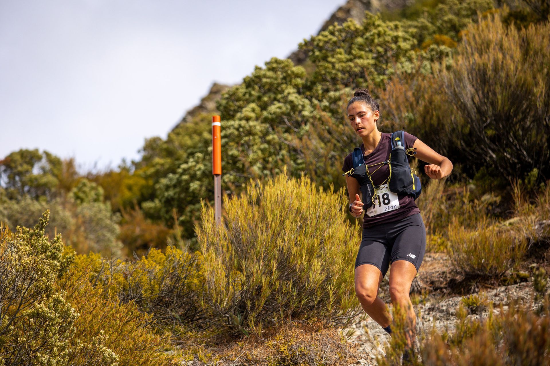 A woman is running on a trail in the woods.