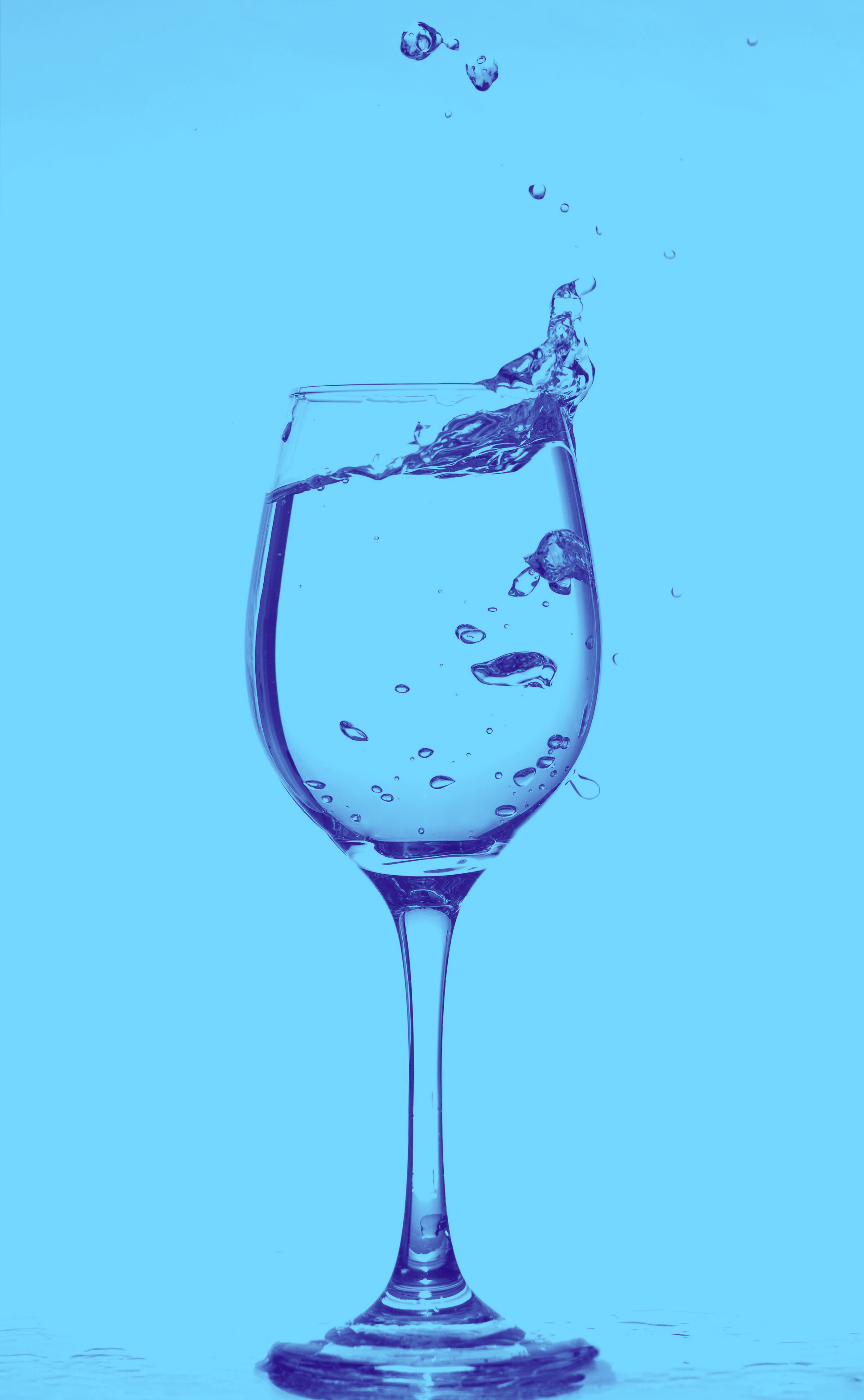 Clear wine glass with water splashing and droplets isolated on a white background
